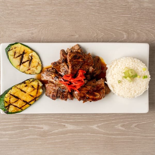 Grilled short ribs with red ginger, white rice, and grilled zucchini on a white plate.
